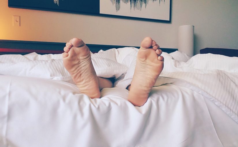 personne allongée dans un lit avec les pieds qui dépassent